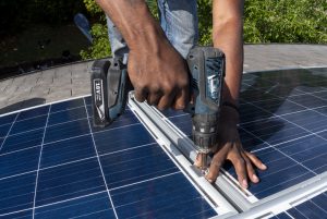 Close up man using power tool to secure solar panel with screws